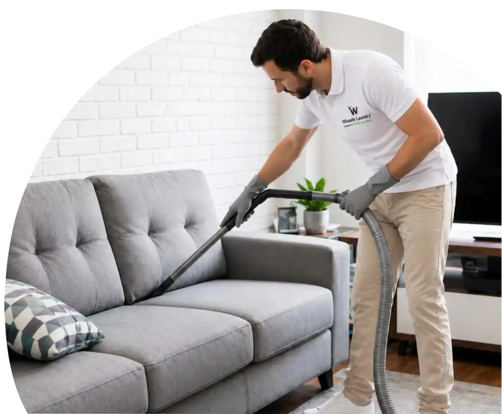 Waasle Laundry cleaner vacuuming a grey sofa for professional sofa cleaning service.